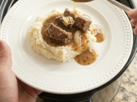 Slow cooker cowboy butter pepper sirloin tips in a black crockpot with steam rising