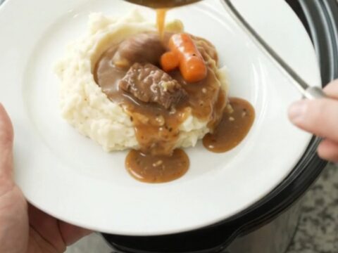 Slow cooker sirloin tips with carrots and potatoes in a rich butter sauce, served in a white bowl.