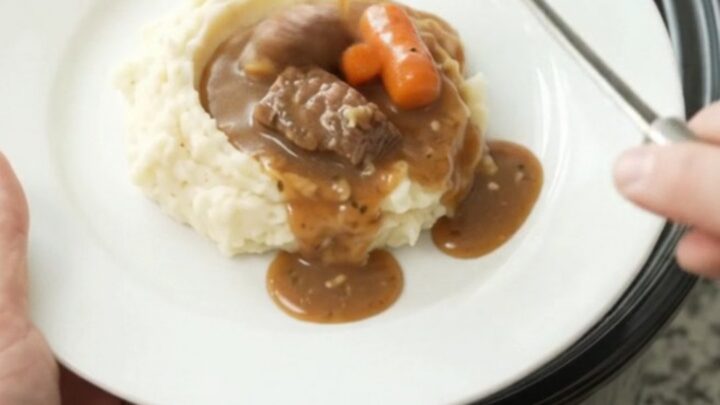 Slow cooker sirloin tips with carrots and potatoes in a rich butter sauce, served in a white bowl.