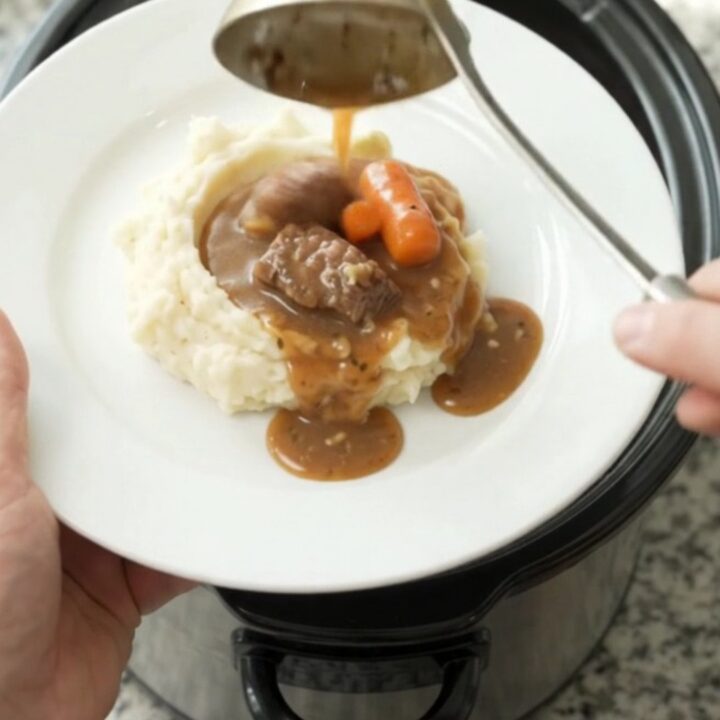 Slow cooker sirloin tips with carrots and potatoes in a rich butter sauce, served in a white bowl.