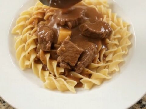 Slow cooker full of sirloin tips, green beans, and potatoes in a creamy brown gravy