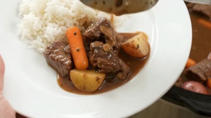 Bourbon gravy sirloin tips with carrots and potatoes in a slow cooker, steam rising