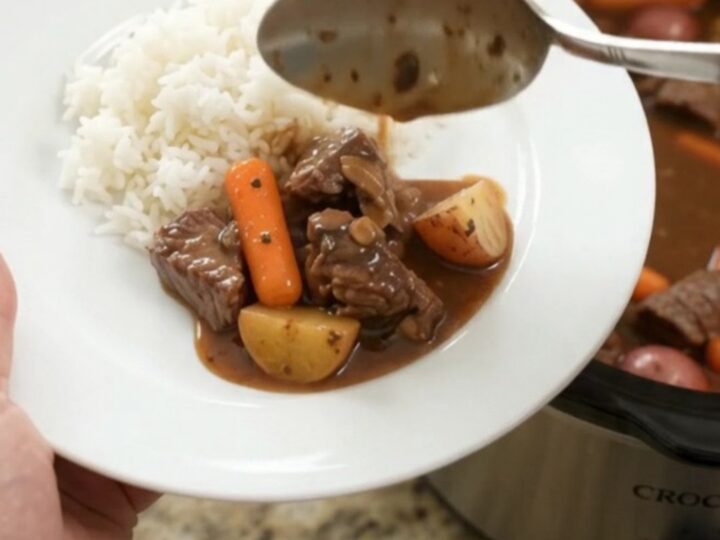 Bourbon gravy sirloin tips with carrots and potatoes in a slow cooker, steam rising