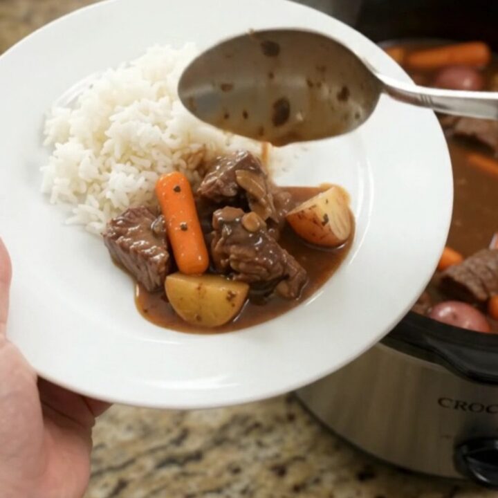 Bourbon gravy sirloin tips with carrots and potatoes in a slow cooker, steam rising
