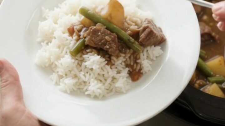 Slow cooker sirloin tips with green beans and potatoes in bourbon gravy, served in a black crockpot.