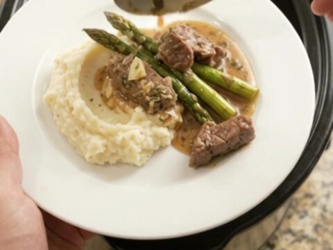 Slow cooker filled with tender sirloin tips and asparagus in a golden garlic-herb butter sauce