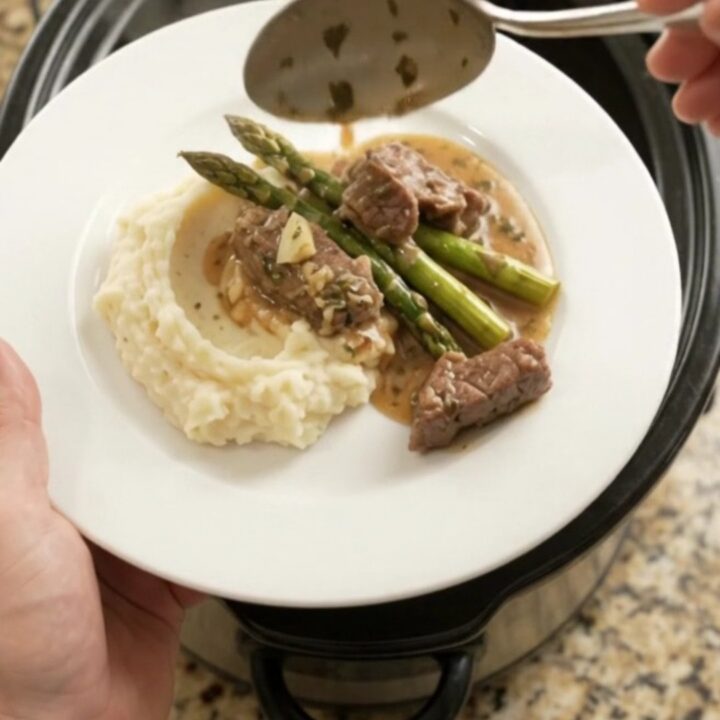 Slow cooker filled with tender sirloin tips and asparagus in a golden garlic-herb butter sauce