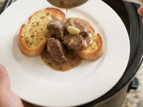 Slow cooker full of creamy sirloin tips and asparagus with melted Gruyère sauce