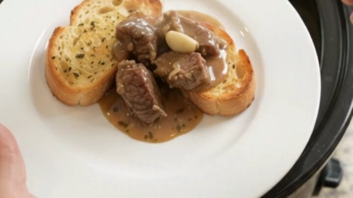 Slow cooker full of creamy sirloin tips and asparagus with melted Gruyère sauce