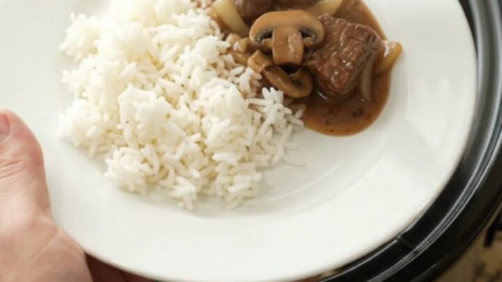 Bourbon gravy mushroom ribeye bites in a slow cooker, with a spoon lifting a bite.