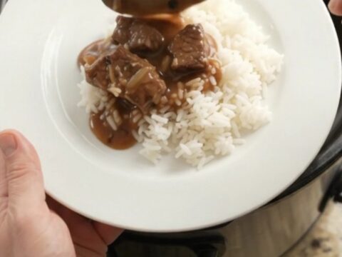 Bourbon gravy sirloin tips with pearl onions and carrots in a slow cooker, topped with melting butter.