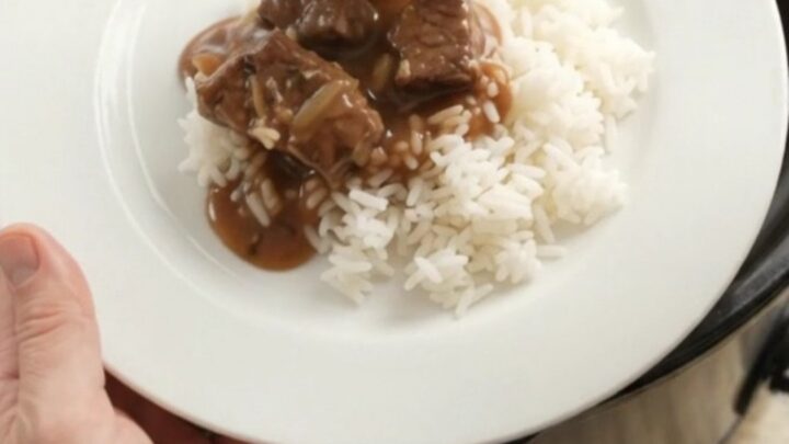 Bourbon gravy sirloin tips with pearl onions and carrots in a slow cooker, topped with melting butter.