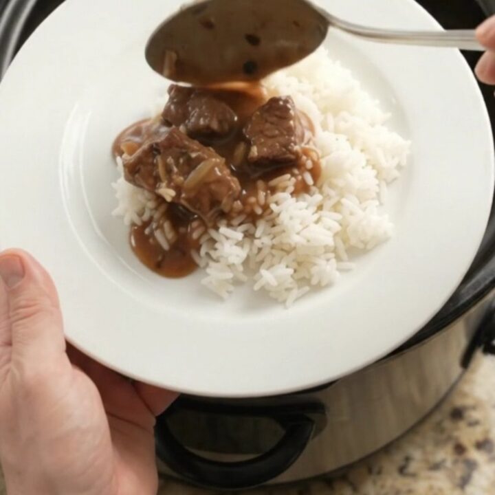 Bourbon gravy sirloin tips with pearl onions and carrots in a slow cooker, topped with melting butter.