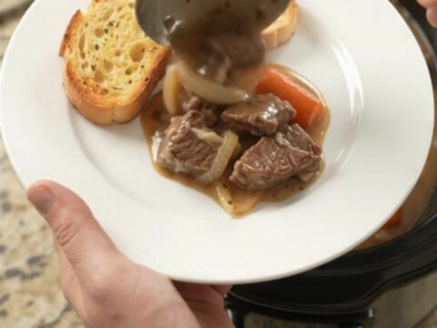 Slow-cooker sirloin tips with pearl onions and carrots in a creamy Gruyère sauce, bubbling in the crockpot.