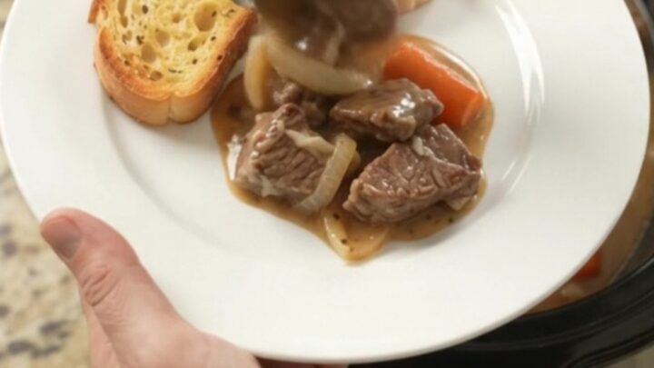 Slow-cooker sirloin tips with pearl onions and carrots in a creamy Gruyère sauce, bubbling in the crockpot.