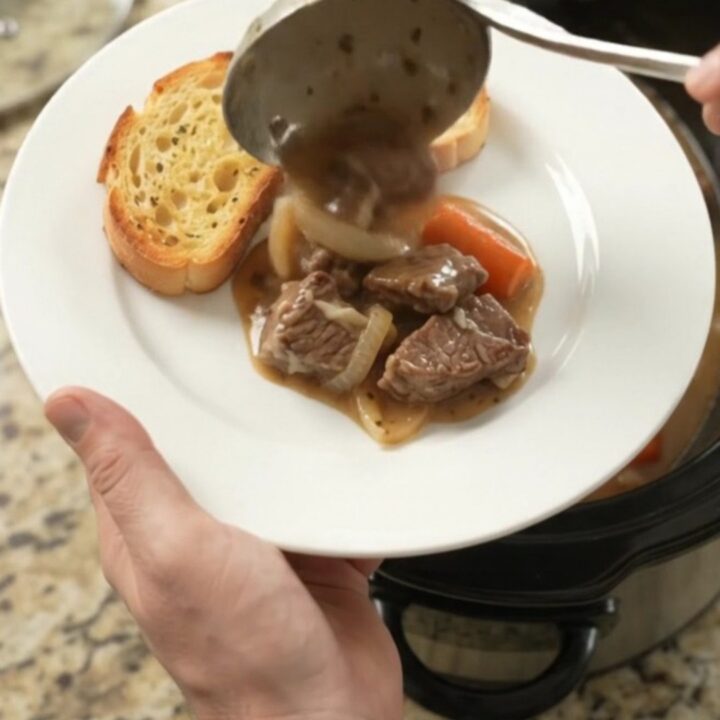 Slow-cooker sirloin tips with pearl onions and carrots in a creamy Gruyère sauce, bubbling in the crockpot.