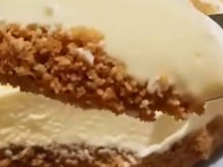 A thick, luscious slice of creamy white cheesecake with a golden biscuit base on a plate.