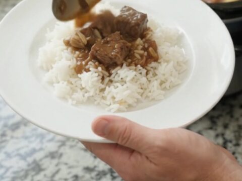 Slow cooker filled with ribeye bites and baby potatoes in a rich bourbon gravy, topped with butter pats.