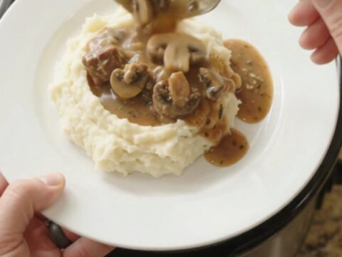 Slow cooker filled with ribeye bites, broccoli, and mushrooms in a buttery au jus sauce.