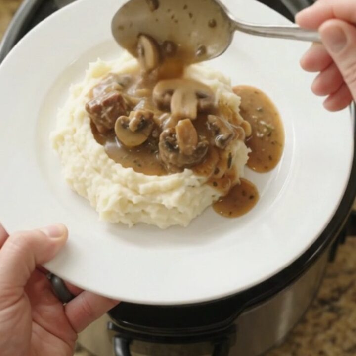 Slow cooker filled with ribeye bites, broccoli, and mushrooms in a buttery au jus sauce.