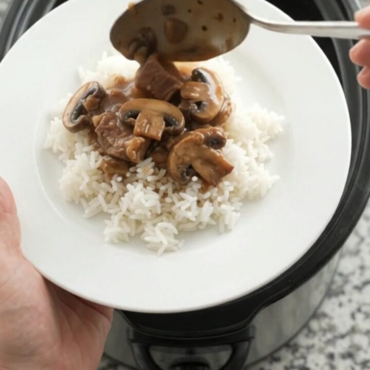 Bourbon gravy portobello ribeye bites in a slow cooker, topped with butter pats