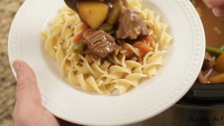 Slow cooker filled with tender ribeye bites, green beans, and potatoes in a creamy gravy