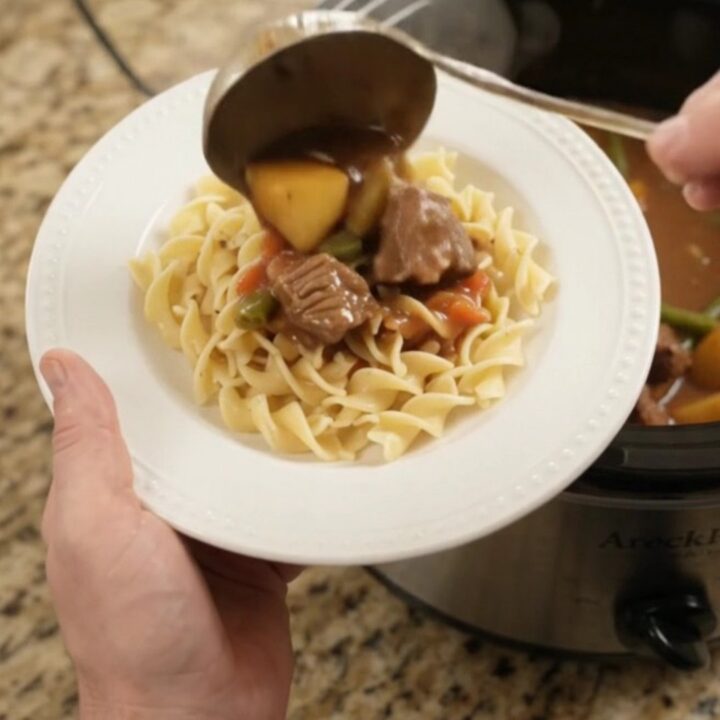 Slow cooker filled with tender ribeye bites, green beans, and potatoes in a creamy gravy