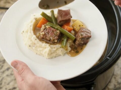 Slow cooker with ribeye bites, green beans, and potatoes in a buttery au jus