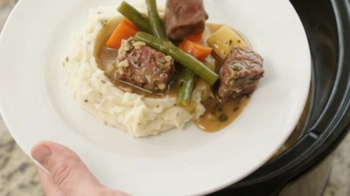 Slow cooker with ribeye bites, green beans, and potatoes in a buttery au jus