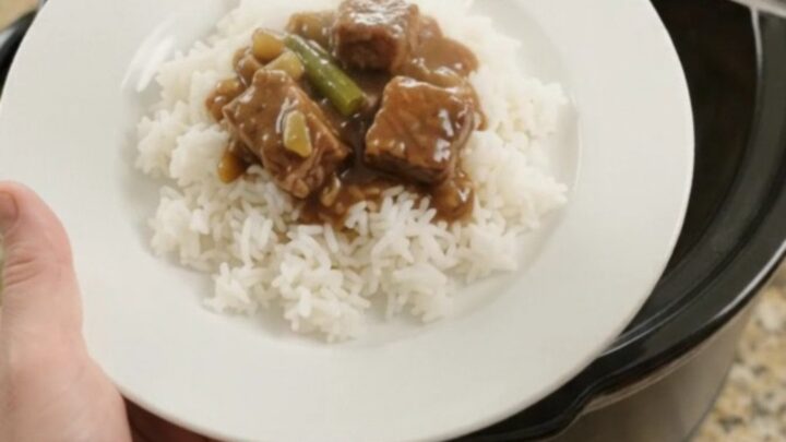 Slow cooker with tender ribeye bites, green beans, and potatoes in bourbon gravy