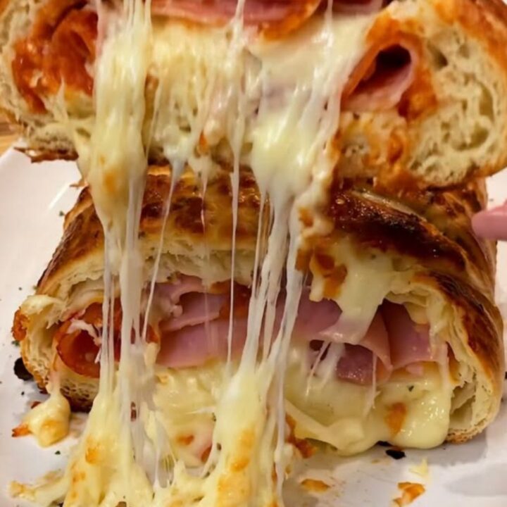 A golden, crusty pizza stromboli sliced open to reveal melted mozzarella, pepperoni, and ham.