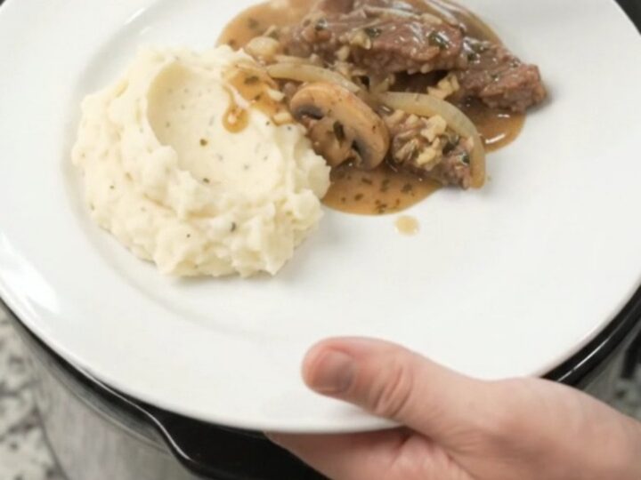 Cowboy butter mushroom flank steak in a slow cooker, bubbling in rich gravy