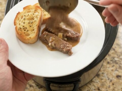 Slow cooker full of tender flank steak and potatoes in creamy Gruyère sauce