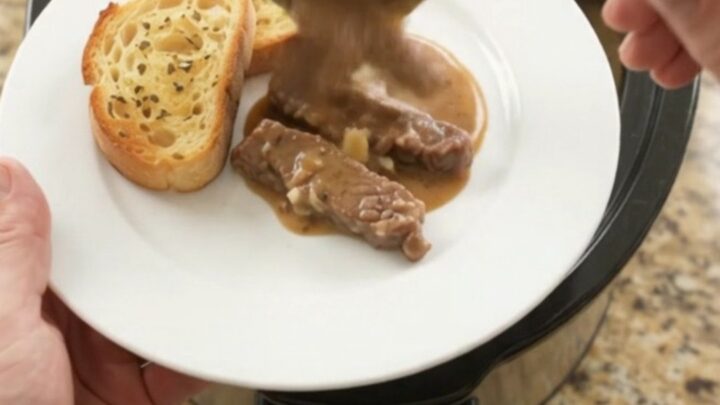 Slow cooker full of tender flank steak and potatoes in creamy Gruyère sauce