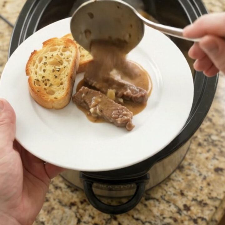 Slow cooker full of tender flank steak and potatoes in creamy Gruyère sauce