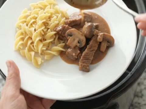 Slow cooker filled with tender flank steak, broccoli, and mushrooms in a creamy brown gravy.