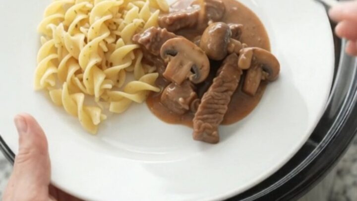 Slow cooker filled with tender flank steak, broccoli, and mushrooms in a creamy brown gravy.