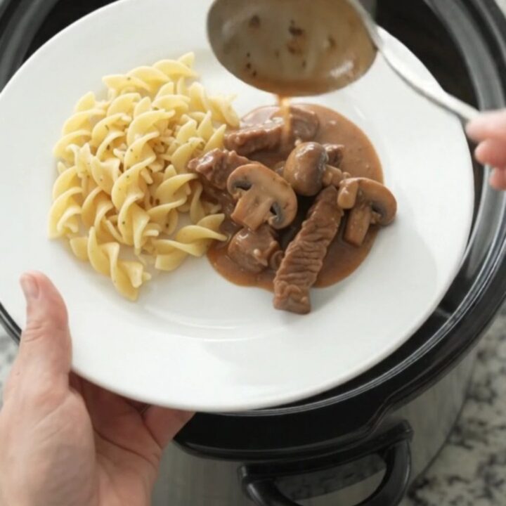 Slow cooker filled with tender flank steak, broccoli, and mushrooms in a creamy brown gravy.