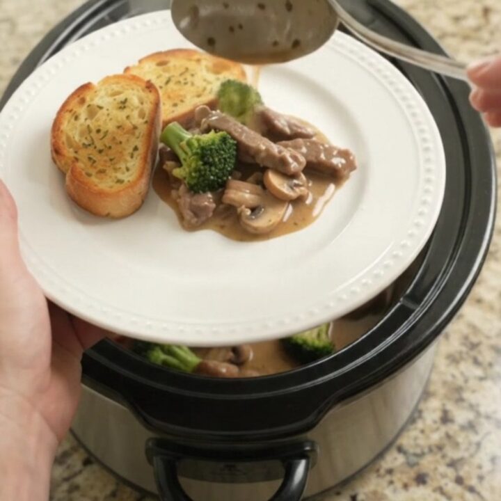 Slow cooker filled with creamy Gruyère sauce, tender flank steak, broccoli, and mushrooms.