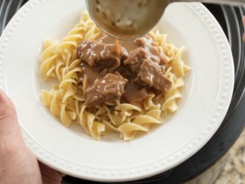 Slow cooker full of tender flank steak, carrots, and potatoes in creamy gravy