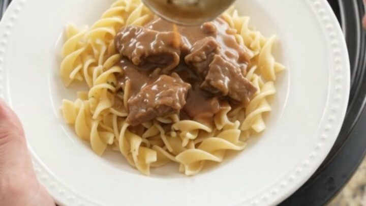 Slow cooker full of tender flank steak, carrots, and potatoes in creamy gravy
