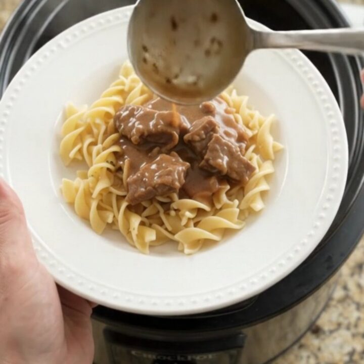 Slow cooker full of tender flank steak, carrots, and potatoes in creamy gravy