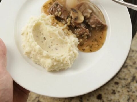Slow cooker with tender flank steak, portobello mushrooms, and shallots in garlic-herb butter au jus