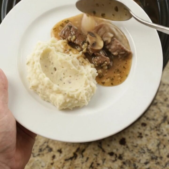 Slow cooker with tender flank steak, portobello mushrooms, and shallots in garlic-herb butter au jus