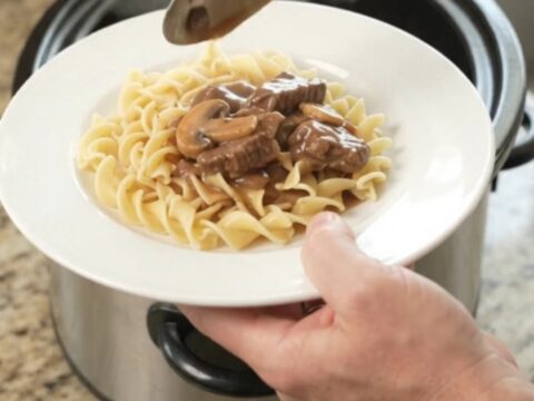 Slow cooker full of braised flank steak, portobello mushrooms, and shallots in a rich sour cream gravy.