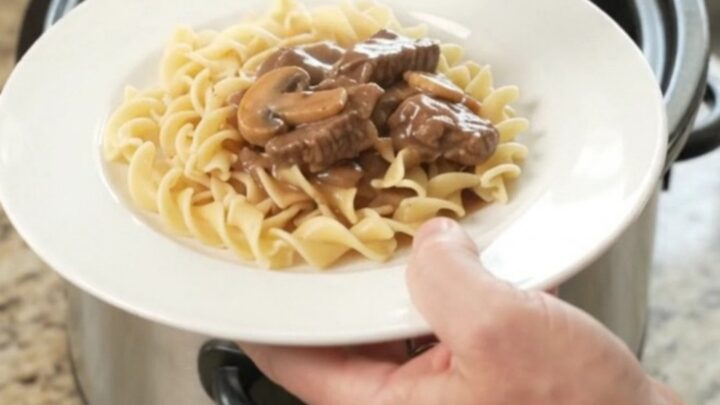 Slow cooker full of braised flank steak, portobello mushrooms, and shallots in a rich sour cream gravy.
