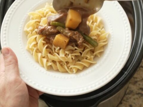 Slow cooker with tender flank steak, green beans, and potatoes in a rich sour cream gravy