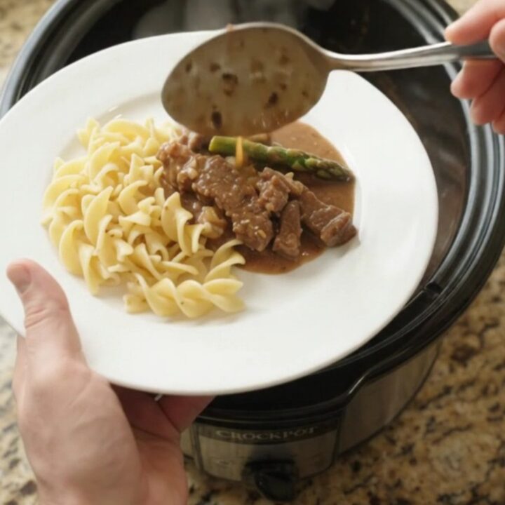 Slow cooker flank steak and asparagus in creamy gravy, served in the crockpot