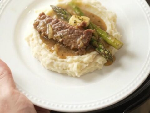 Slow cooker filled with tender flank steak and asparagus in a golden garlic butter au jus.