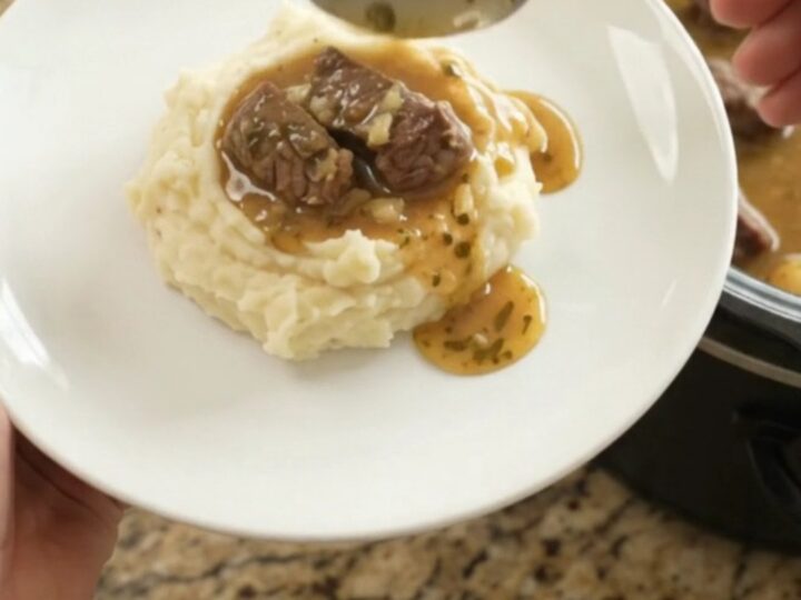 Slow cooker full of tender beef tips and golden potatoes in a buttery au jus